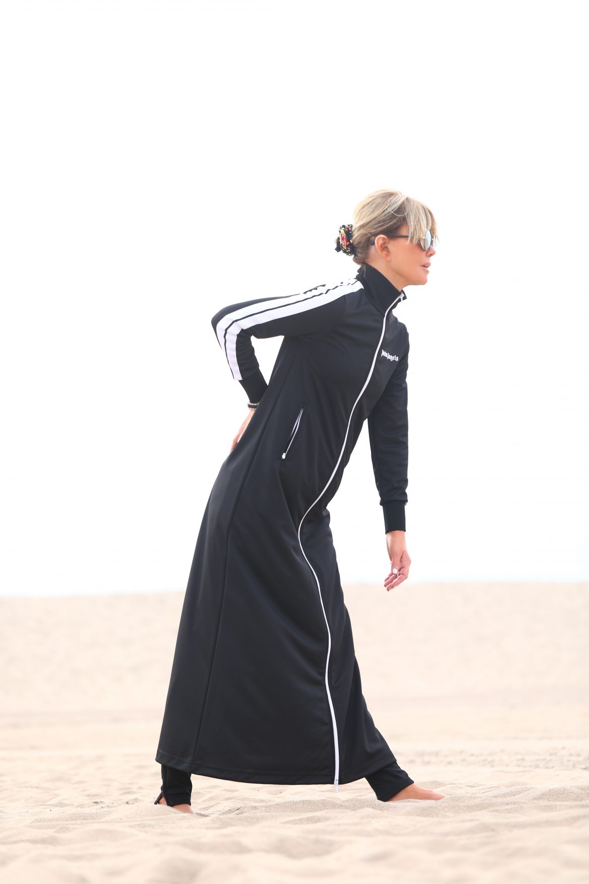 Laura dunn on the beach on a cloudy day wearing a full body black duster