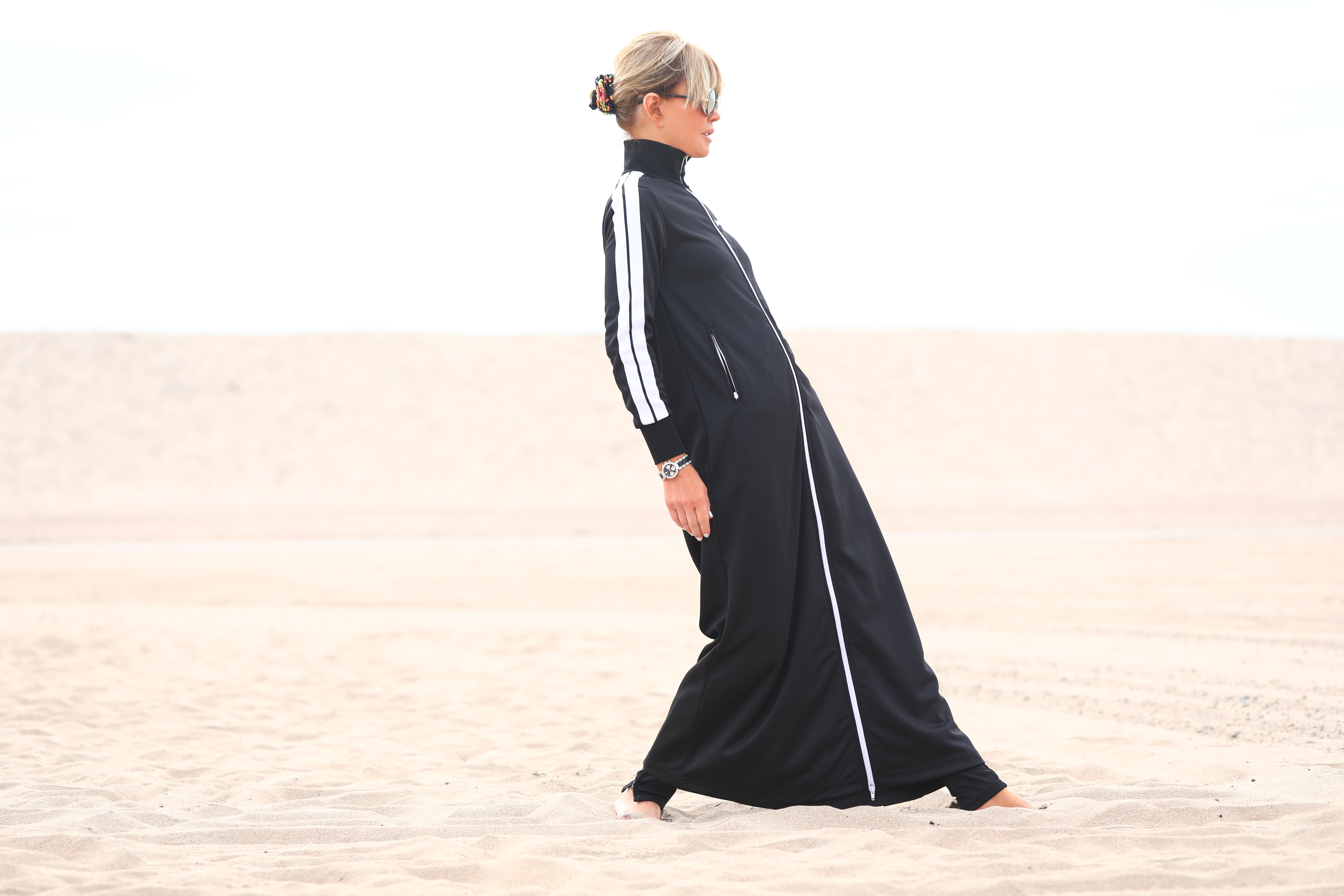 top image of a cool dyptic of Laura dunn wearing a full body black athleisure duster palm angels on Santa Monica beach on a cloudy day