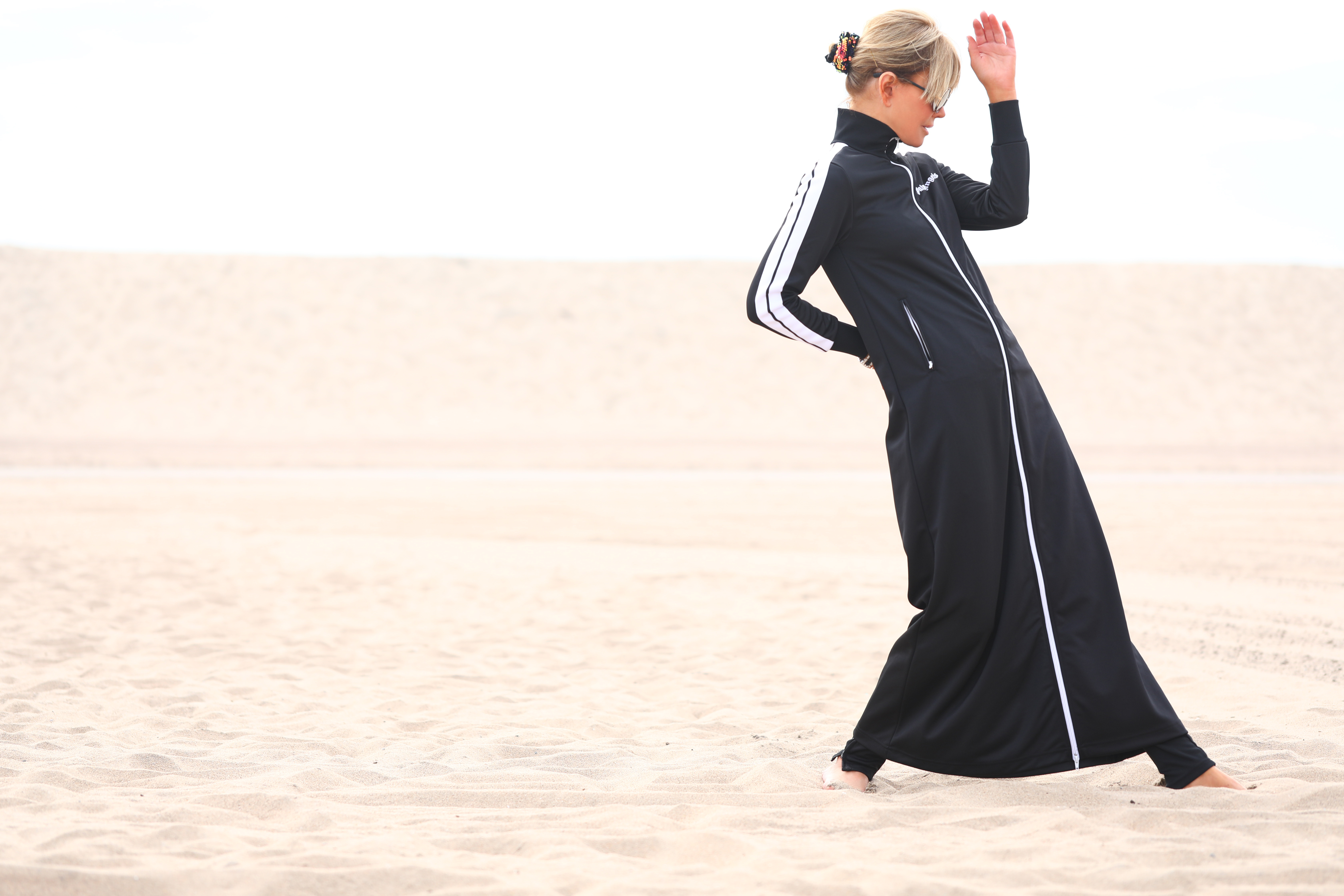 bottom image of a cool dyptic of Laura dunn wearing a full body black athleisure duster palm angels on Santa Monica beach on a cloudy day